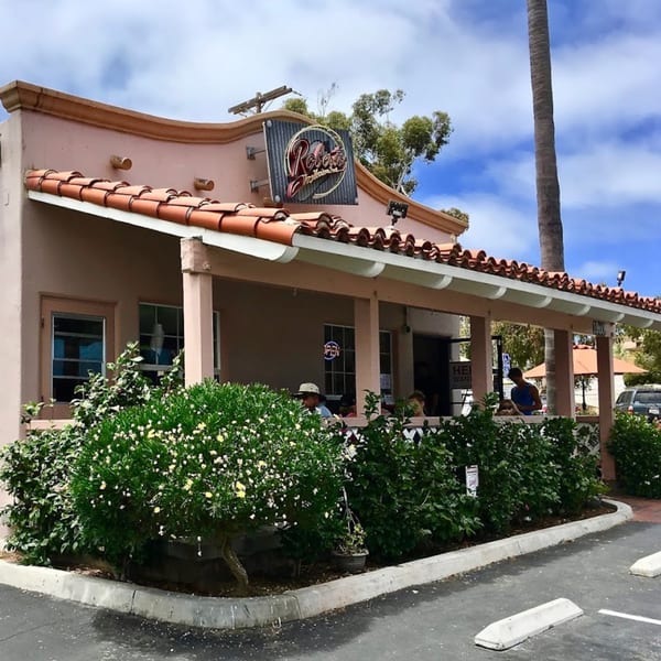 Roberto's Mexican Food restaurant exterior with a patio, red tile roof, and lush green bushes.