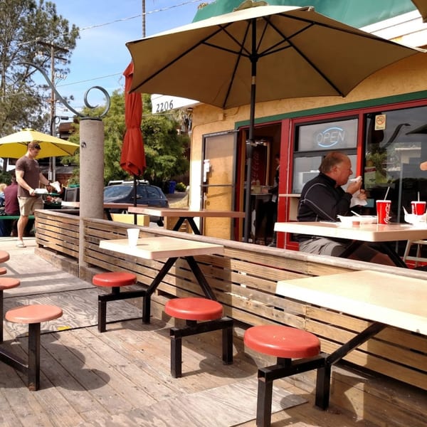 Outdoor patio of Roberto's Mexican Food with customers dining under umbrellas on a sunny day.