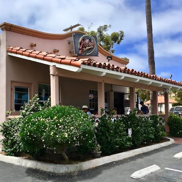 Roberto's Mexican Food restaurant exterior with a red tile roof, outdoor seating, and lush greenery.