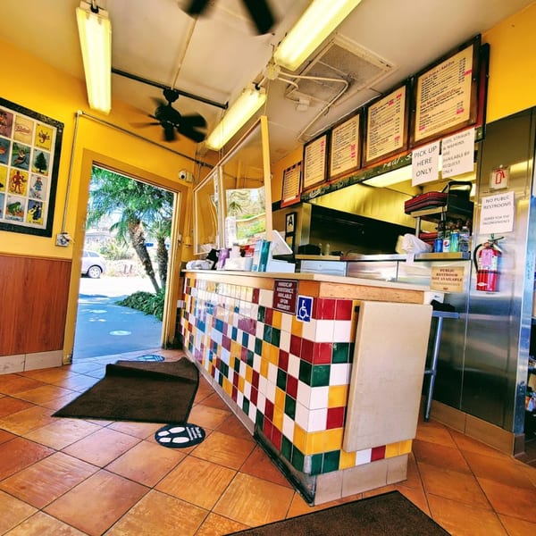 Interior of Roberto's Mexican Food, showing a colorful tiled counter, menu boards, and an open doorway.